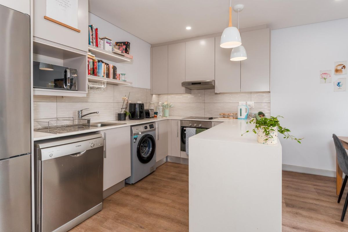 Modern kitchen featuring sleek cabinetry, integrated appliances, a breakfast bar, and wood-look flooring, offering a functional and contemporary cooking space.