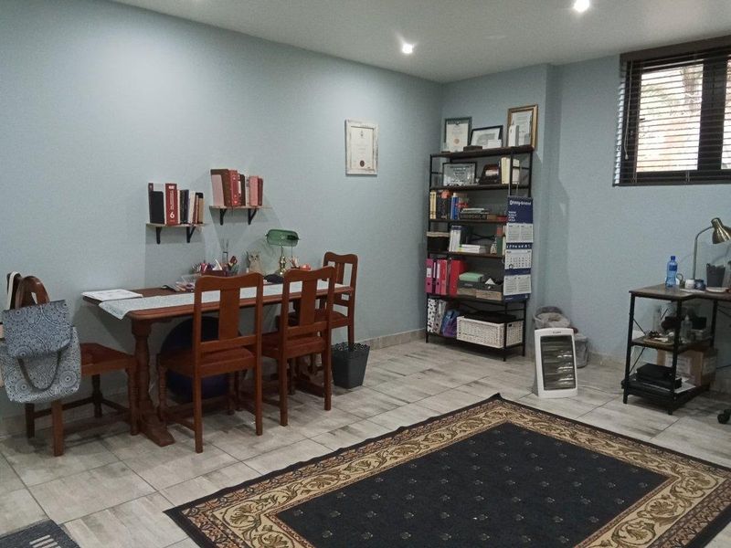 A functional office space featuring tiled flooring, recessed downlighting, and a window with venetian blinds.