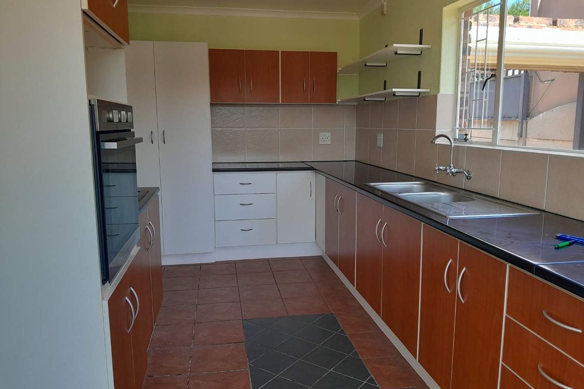Functional kitchen featuring built-in cabinetry, integrated oven, double sink, and tiled splashbacks with ample counter space.