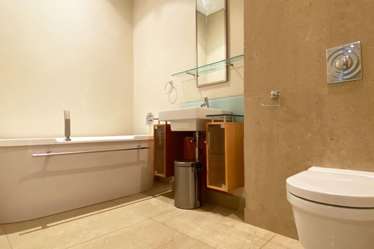 Modern bathroom featuring a wall-mounted vanity, bathtub with chrome fixtures, and a wall-hung toilet with a sleek flush plate.