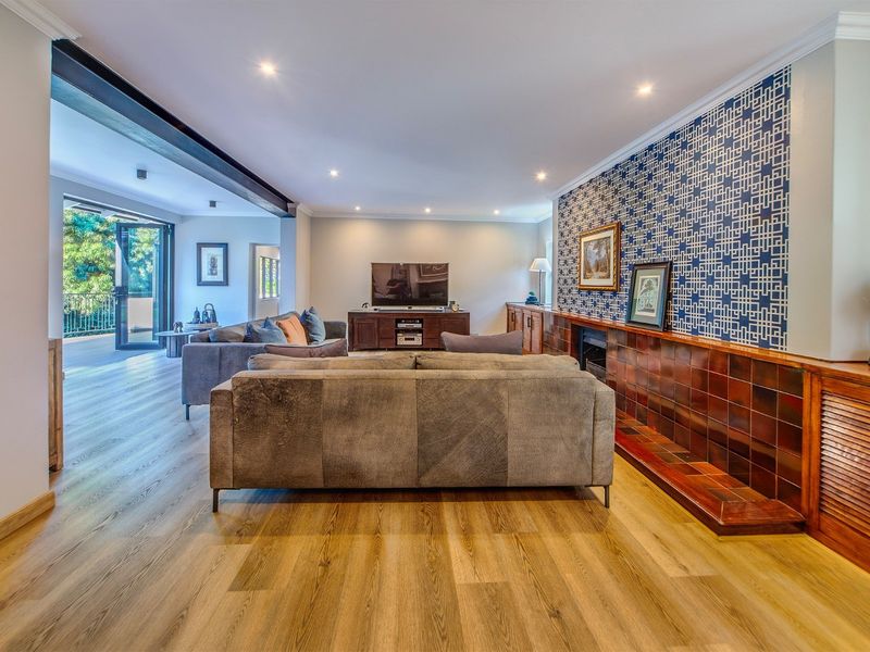 Spacious living room featuring modern laminate flooring, recessed lighting, a built-in fireplace with decorative tiling, and seamless access to an outdoor patio area.