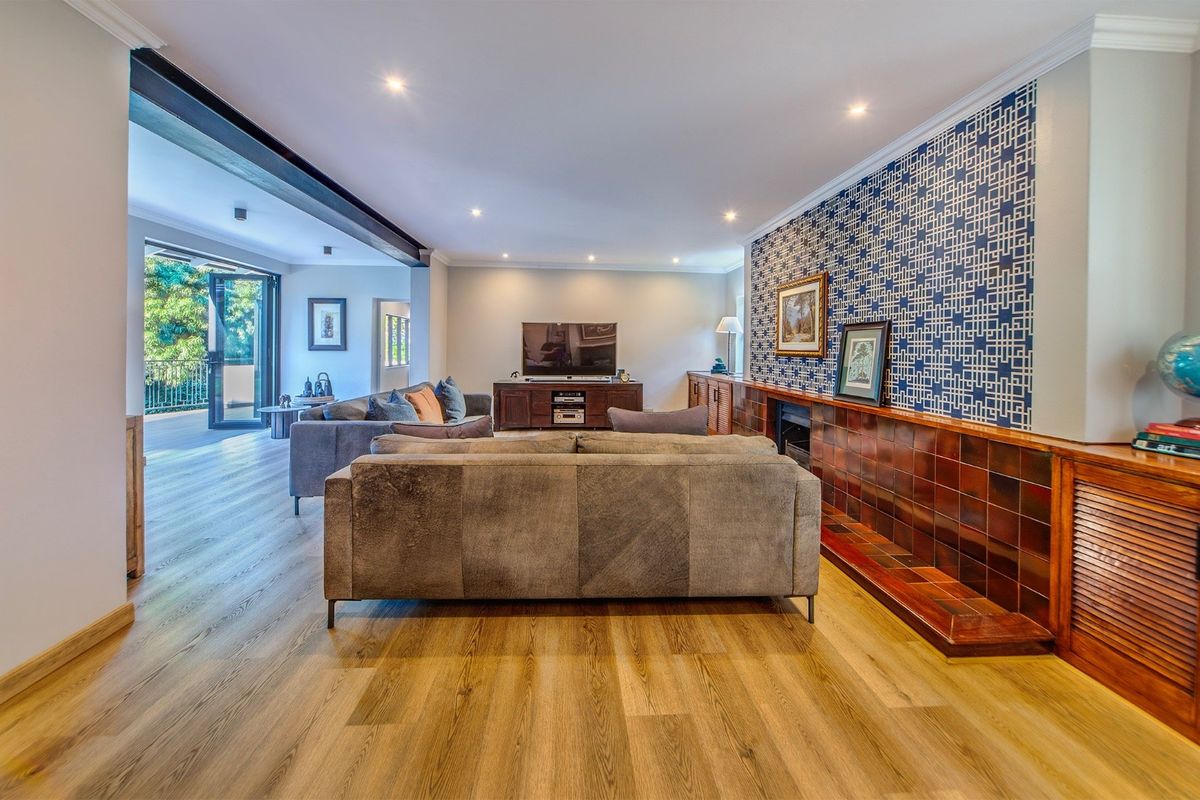 Spacious living room featuring modern laminate flooring, recessed lighting, a built-in fireplace with decorative tiling, and seamless access to an outdoor patio area.