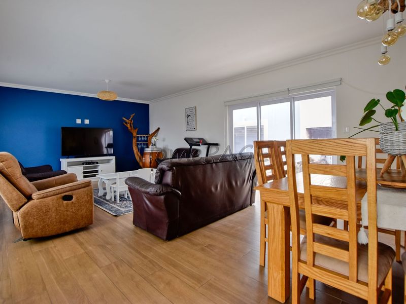 Spacious open-plan living and dining area featuring laminate flooring, a bold blue accent wall, and large sliding glass doors providing natural light.