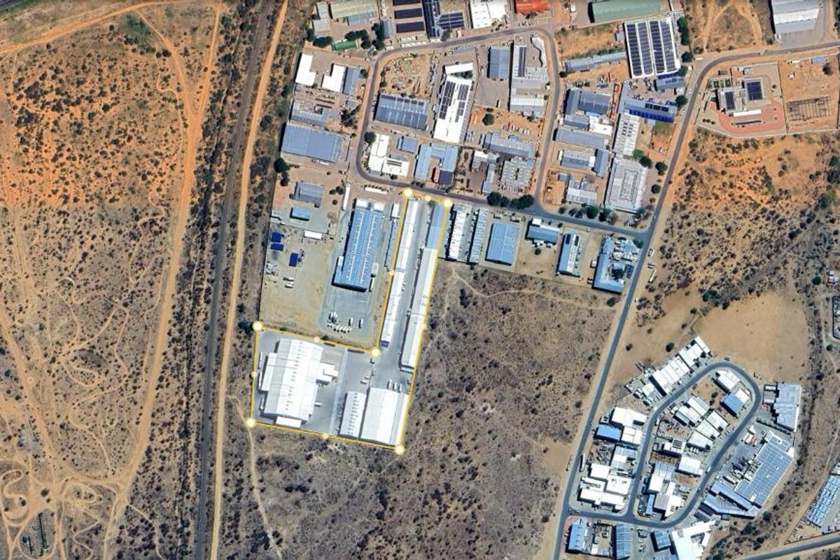 Aerial view of an industrial property complex featuring multiple warehouse structures, paved yard space, and secure perimeter access within an industrial park setting.