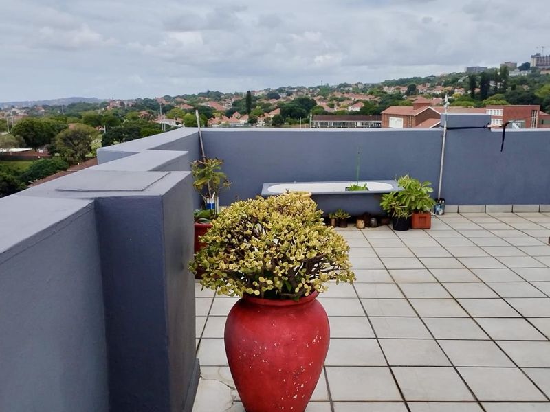 Spacious penthouse balcony featuring tiled flooring, solid perimeter walls, and expansive elevated views of the surrounding neighbourhood.