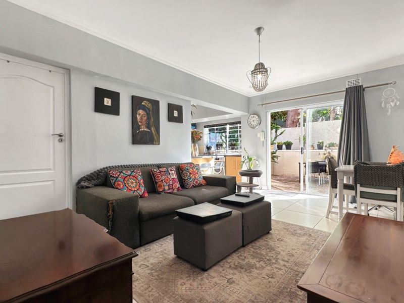 Open plan living area featuring tiled floors, neutral walls, and a sliding glass door providing seamless access to the outdoor patio space.
