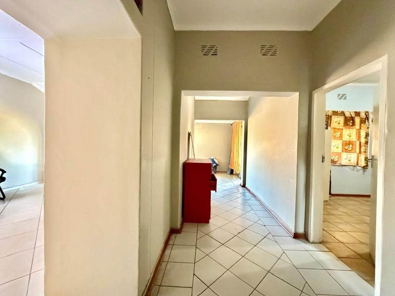A functional office hallway featuring neutral wall finishes and ceramic floor tiles, providing access to multiple connected office spaces.