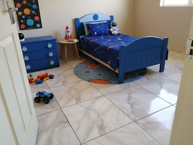 A well-maintained bedroom featuring polished marble-look ceramic floor tiles and neutral wall finishes.
