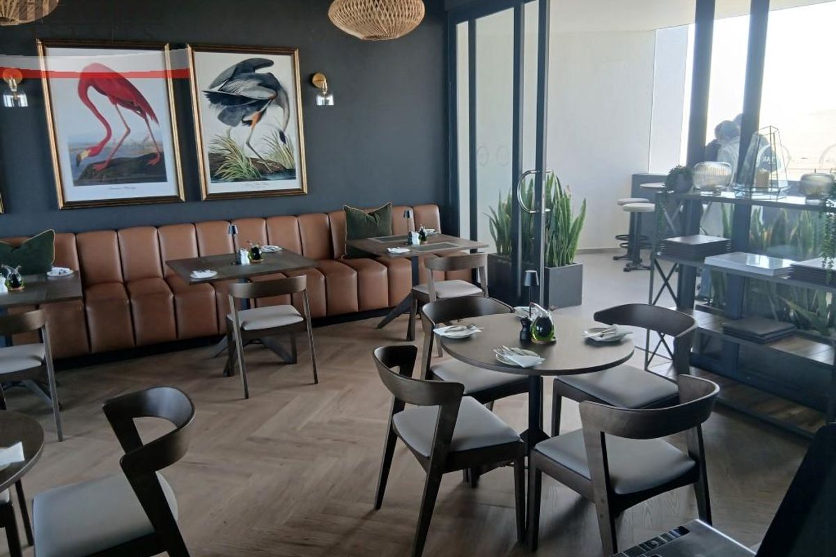 Modern dining or lounge area featuring herringbone timber flooring, dark feature walls, built-in banquette seating, and large sliding glass doors leading to an outdoor space.