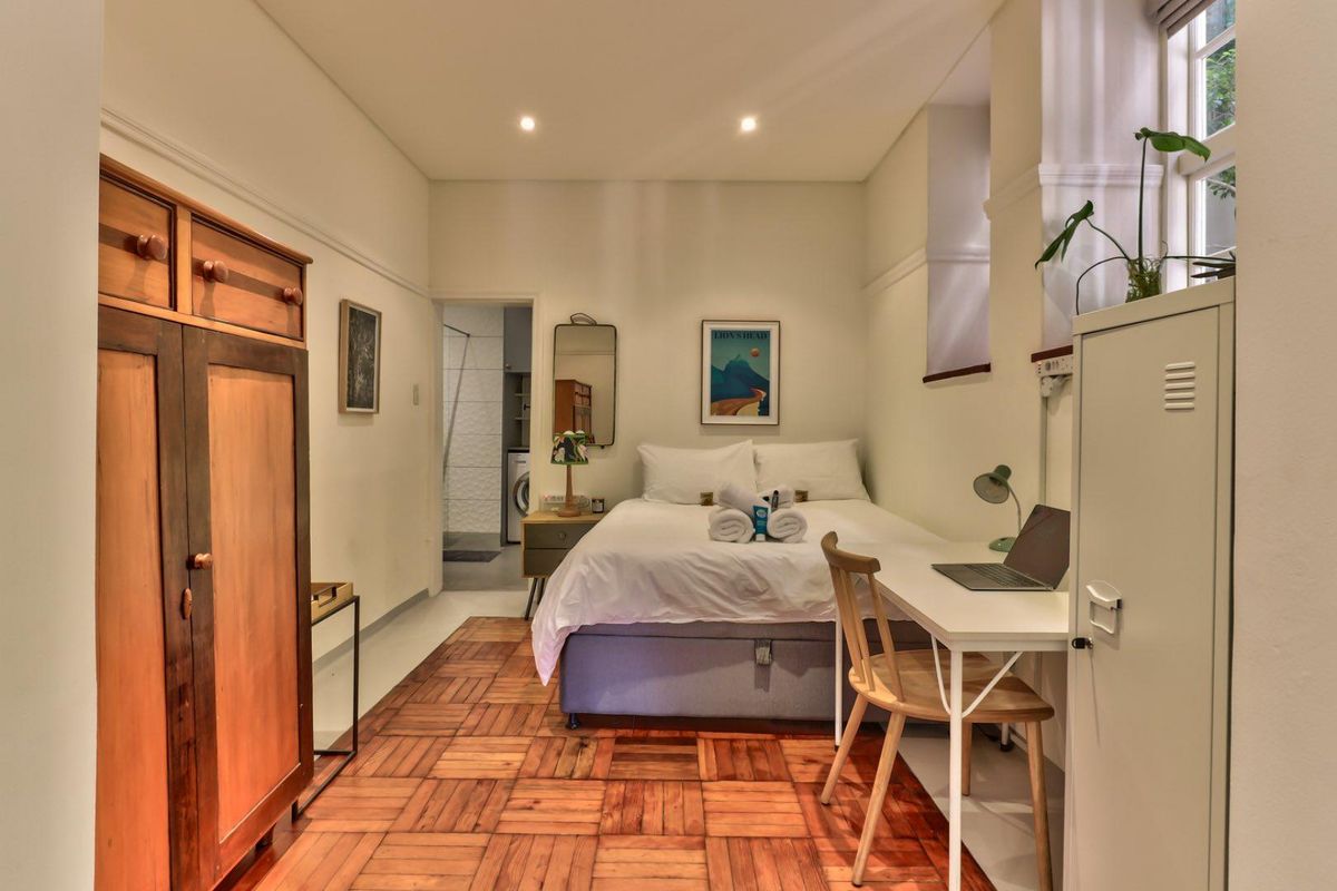A well-maintained bedroom featuring classic parquet flooring, recessed ceiling lighting, and an en-suite bathroom access.