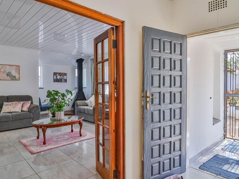 Entrance area featuring tiled flooring, a solid panelled door, and a security gate, leading into a living space with a freestanding fireplace.