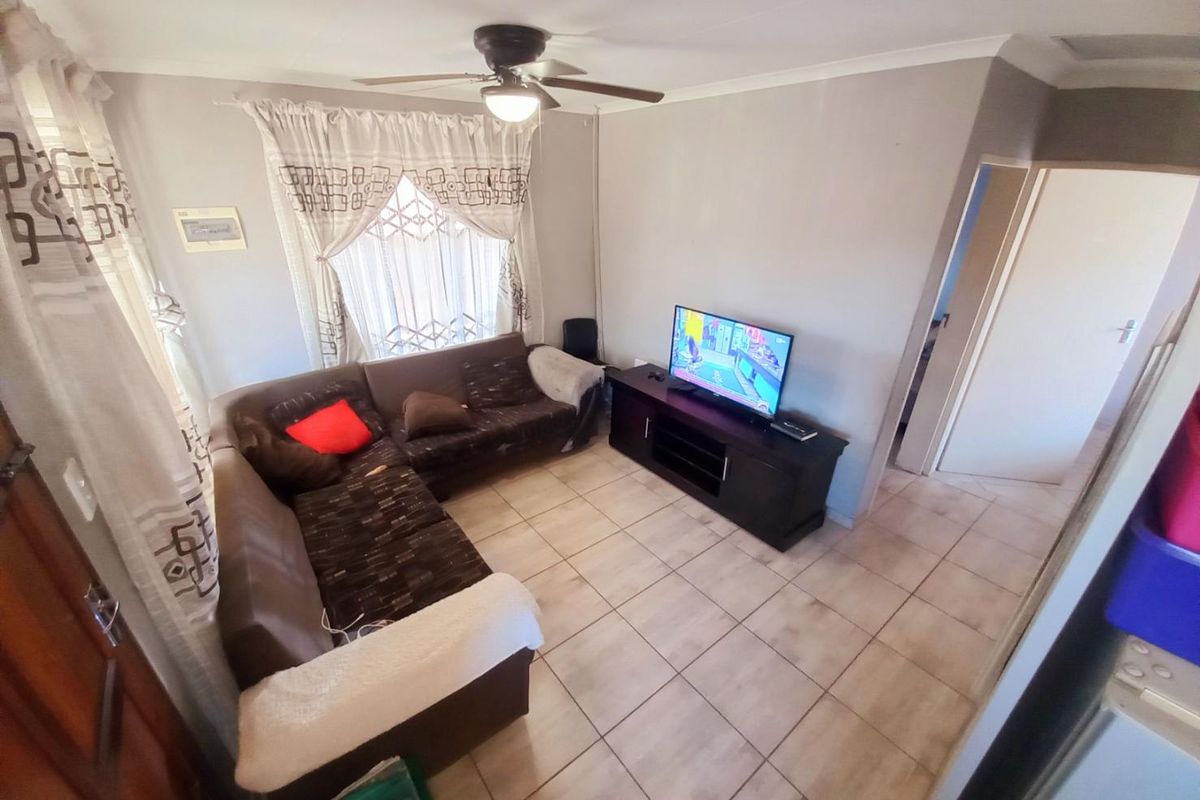 A functional living room featuring tiled flooring, a ceiling fan, and neutral wall finishes, providing a comfortable and practical space for daily relaxation.