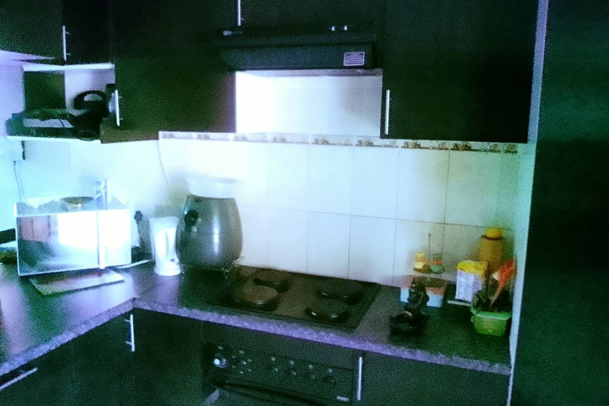 A compact kitchen featuring dark cabinetry, a tiled backsplash, and integrated cooking appliances including an electric hob and oven.