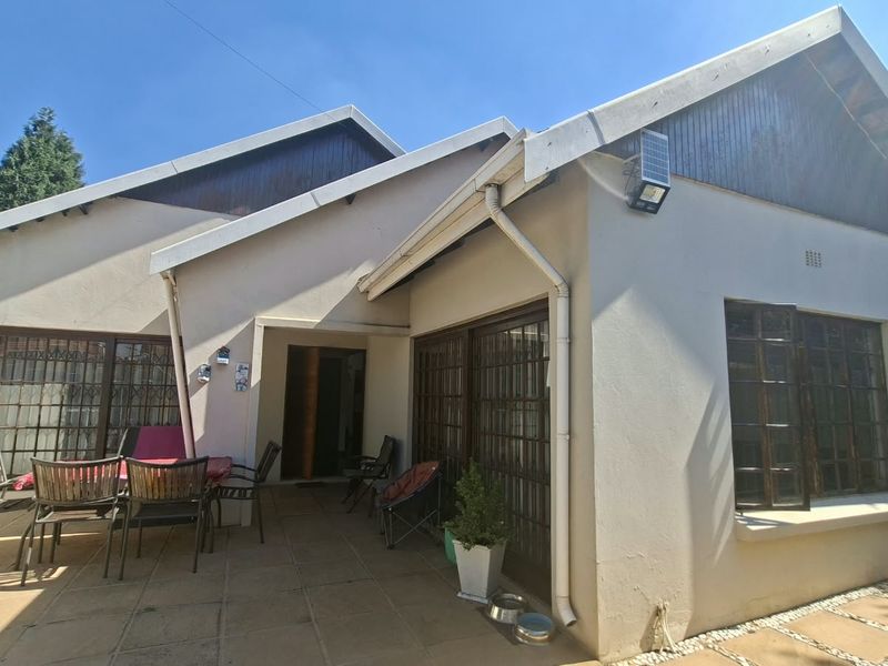 Rear exterior view of the house featuring a paved patio area, sliding glass doors, and solar security lighting.