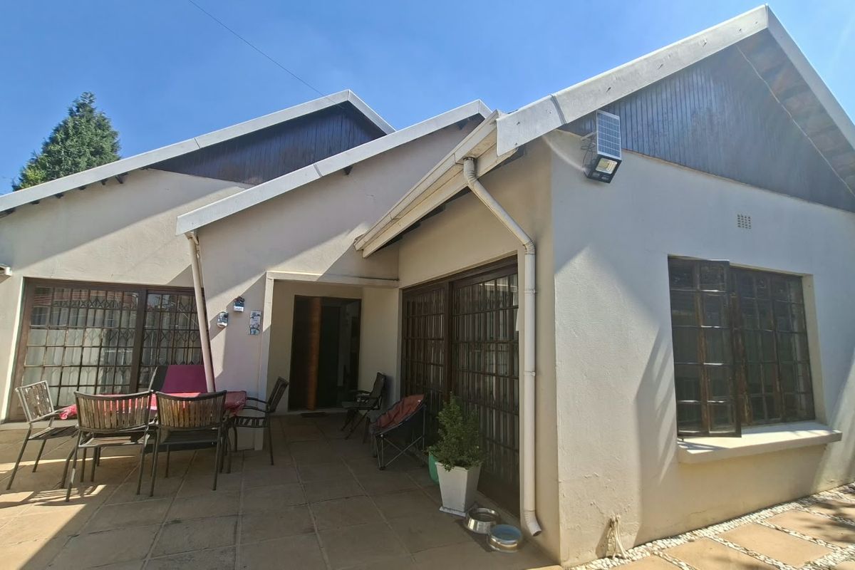 Rear exterior view of the house featuring a paved patio area, sliding glass doors, and solar security lighting.
