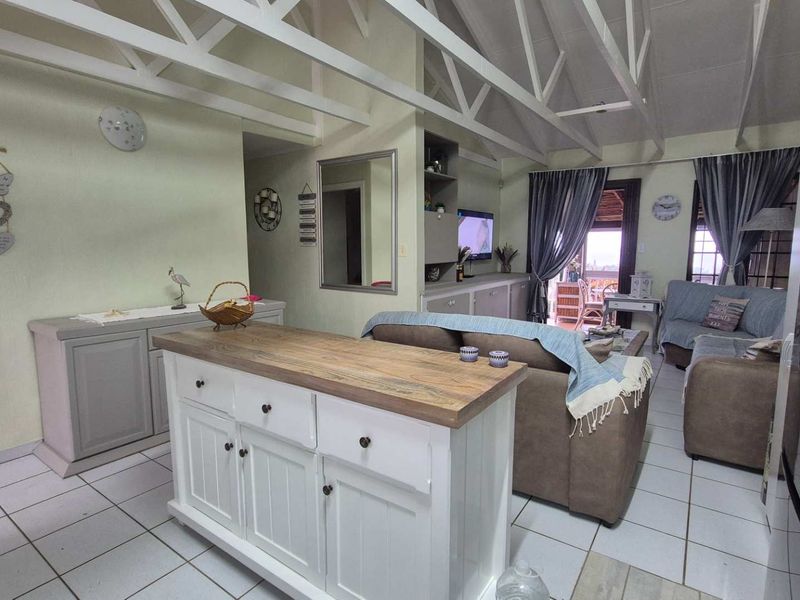 Open-plan living area featuring exposed timber roof trusses, tiled flooring, and built-in cabinetry, creating a bright and functional space.