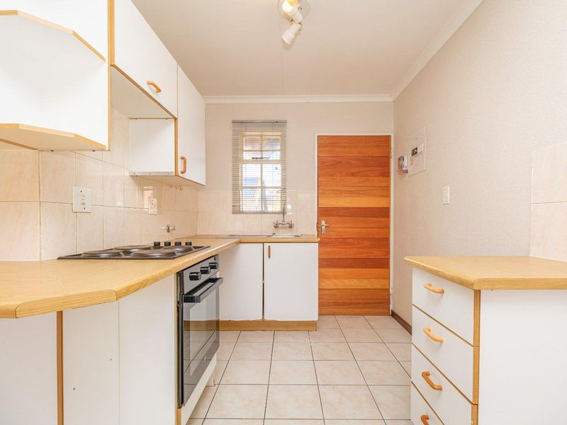 A functional kitchen featuring built-in cabinetry, laminate countertops, a built-in oven with hob, and tiled flooring, providing a clean and practical workspace.