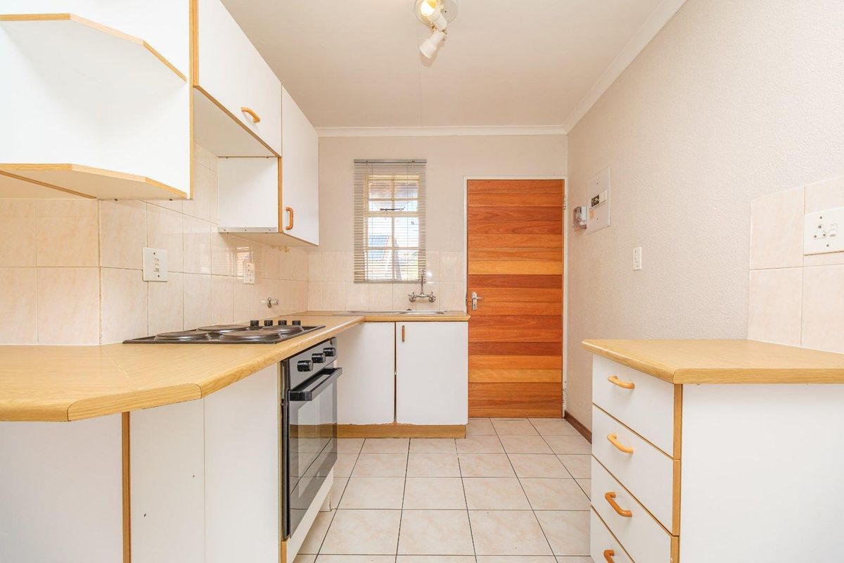 A functional kitchen featuring built-in cabinetry, laminate countertops, a built-in oven with hob, and tiled flooring, providing a clean and practical workspace.