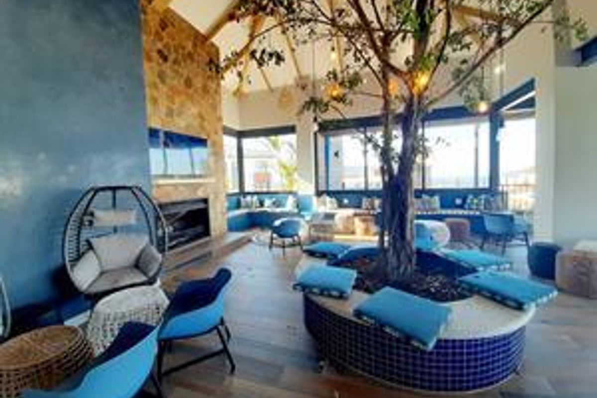 A spacious living area featuring a stone fireplace, vaulted ceilings, timber flooring, and a unique central built-in seating area with integrated planter.