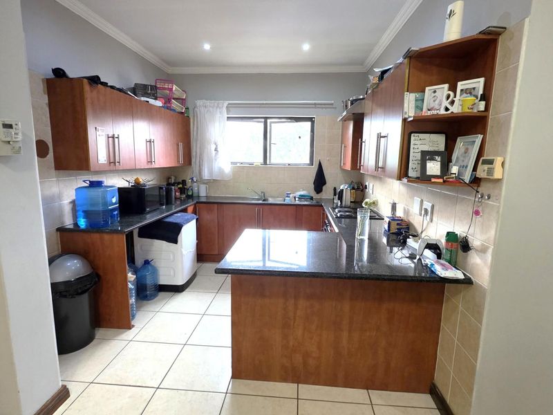 A functional kitchen featuring wooden cabinetry, granite countertops, tiled flooring, and a tiled backsplash, offering ample storage and workspace.