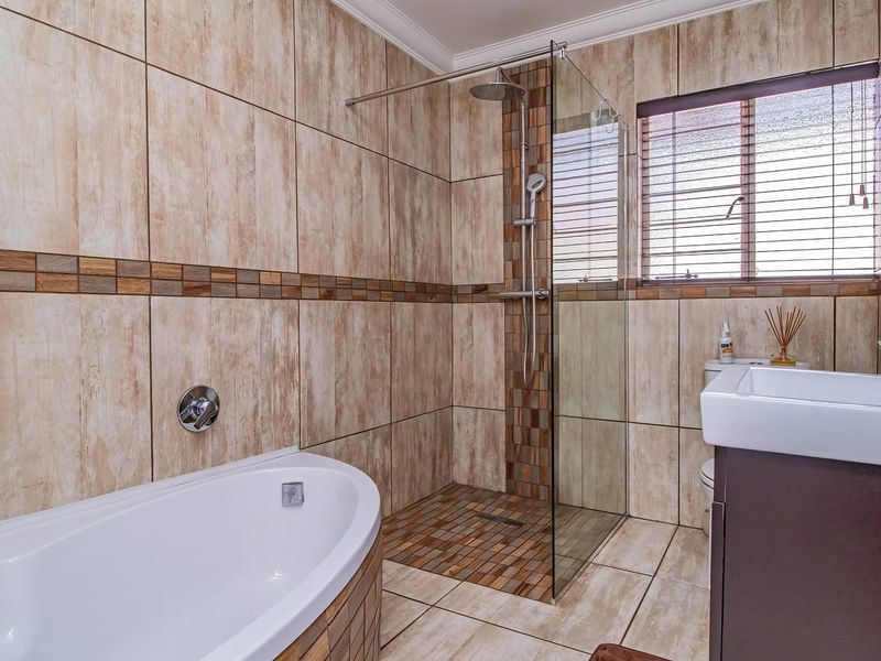 Modern bathroom featuring a freestanding bathtub, a spacious walk-in shower with glass enclosure, and a vanity basin with built-in cabinetry.