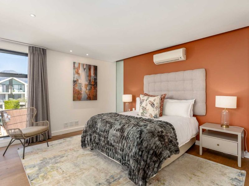 A well-maintained bedroom featuring timber flooring, recessed lighting, a split-system air conditioner, and a large window with natural light.