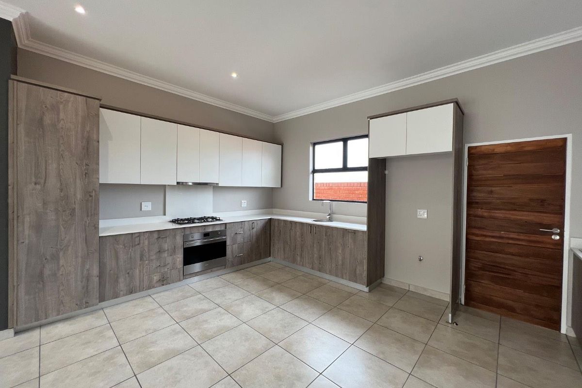 Modern kitchen featuring two-tone cabinetry, stone countertops, built-in oven, gas hob, extractor fan, and tiled flooring.