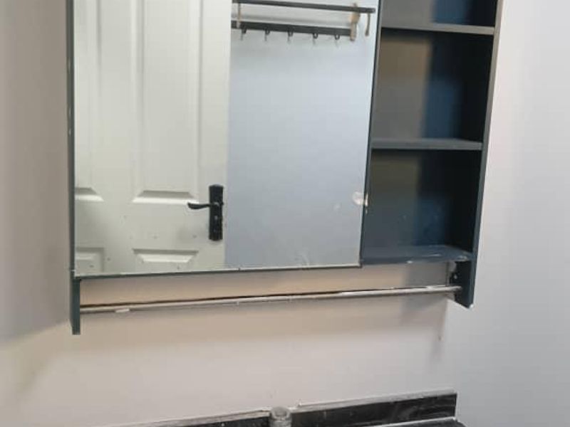 A bathroom vanity area featuring a dark stone countertop, undermount sink, and a matching wall-mounted medicine cabinet with integrated shelving and mirror.