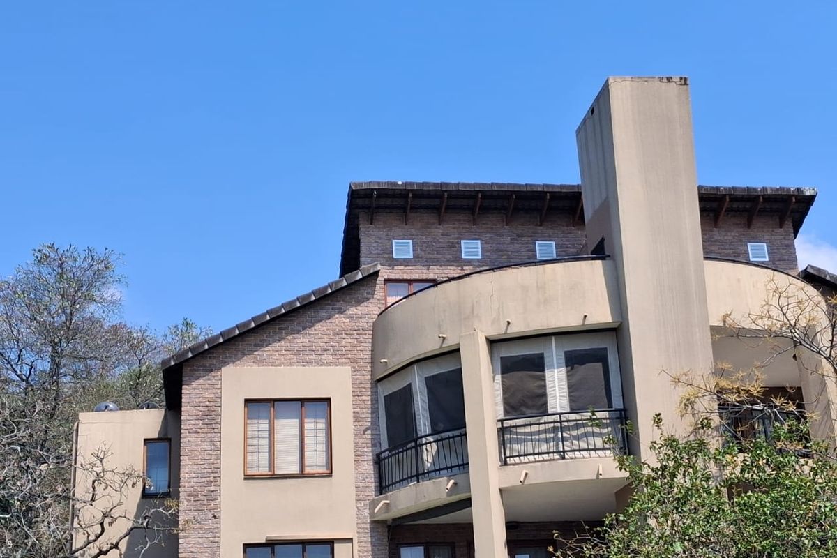 Rear elevation of a multi-story apartment building featuring brick and stucco facade, curved balconies with metal railings, and a prominent chimney stack.