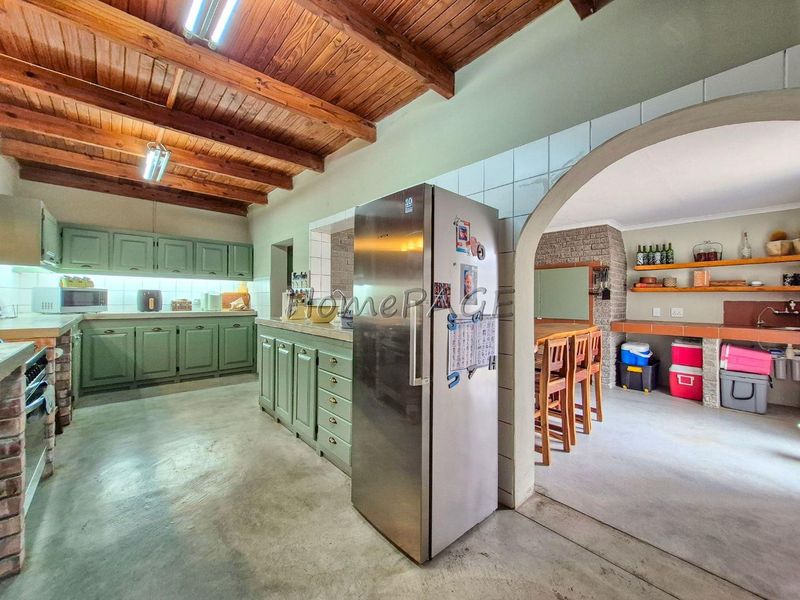 Open plan kitchen and dining area featuring exposed timber beam ceilings, traditional cabinetry, and a brick archway connecting the spaces.