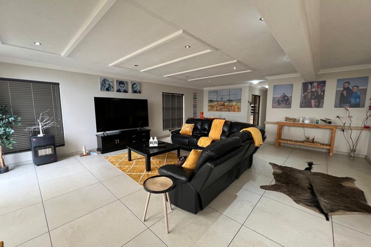 Spacious open-plan living area featuring large format floor tiles, recessed ceiling detailing with integrated downlighting, and venetian blinds.