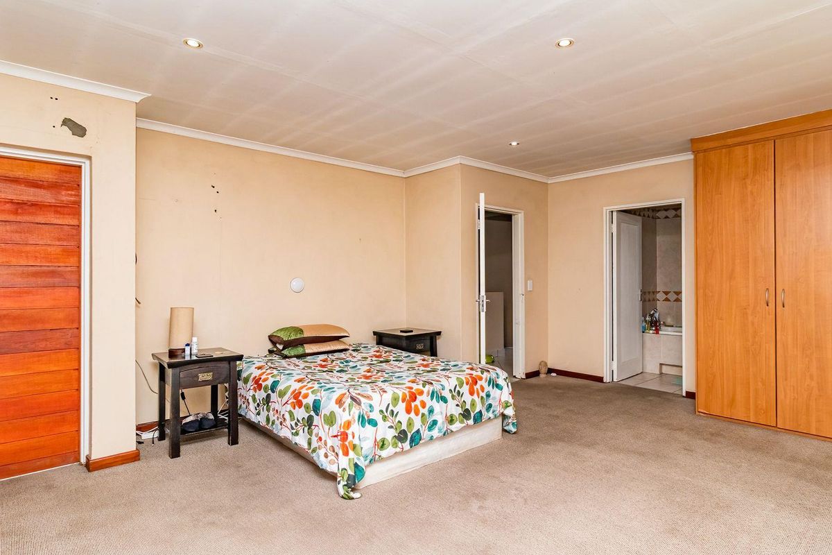 Spacious bedroom featuring built-in wooden cupboards, recessed ceiling lighting, and an en-suite bathroom access.