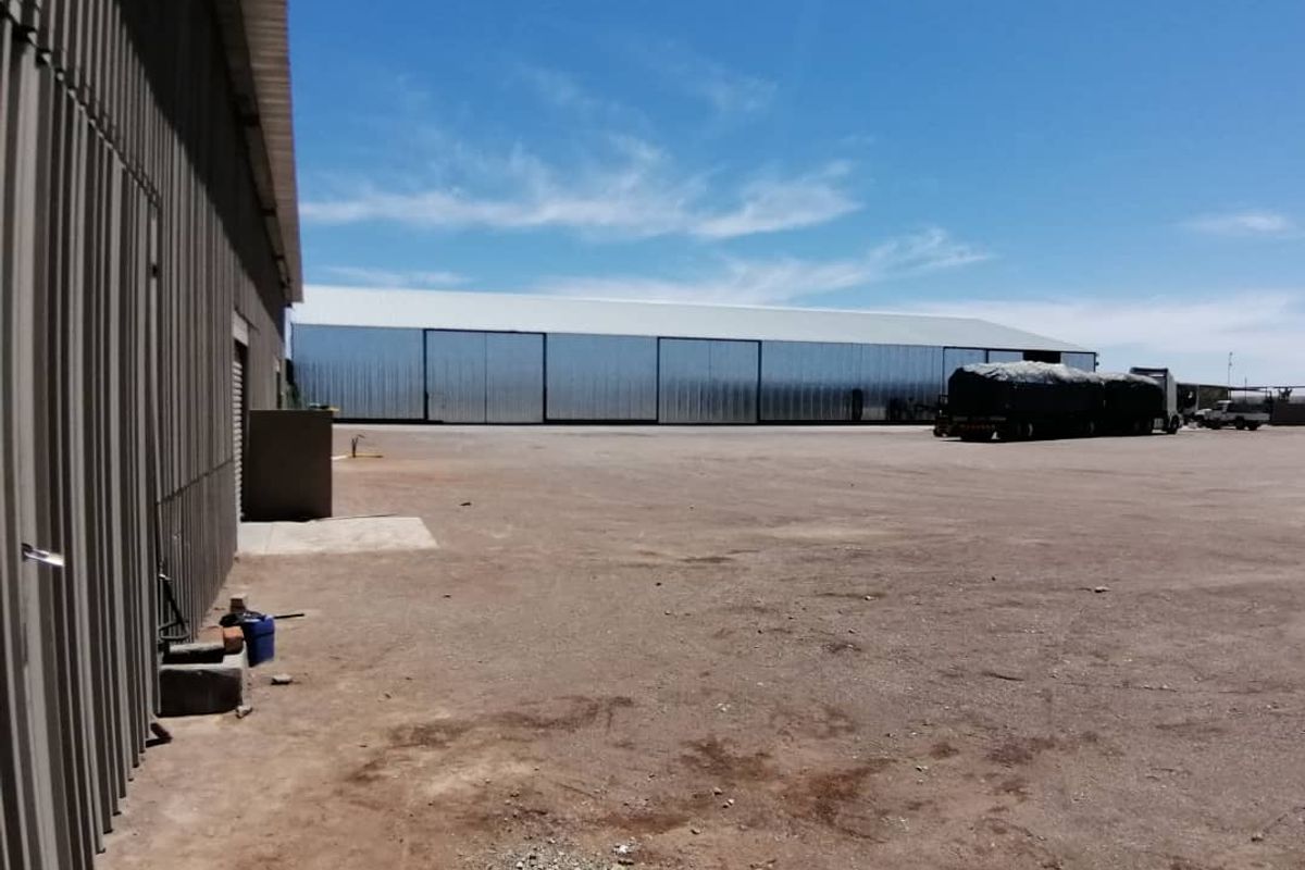 Expansive commercial yard area featuring large industrial metal-clad warehouse structures with wide access doors and ample open space for logistics or storage operations.