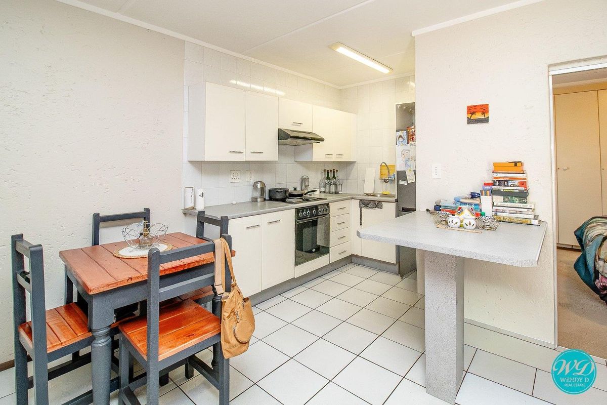 A functional kitchen featuring white cabinetry, a built-in electric stove with extractor fan, tiled flooring, and a convenient breakfast bar.