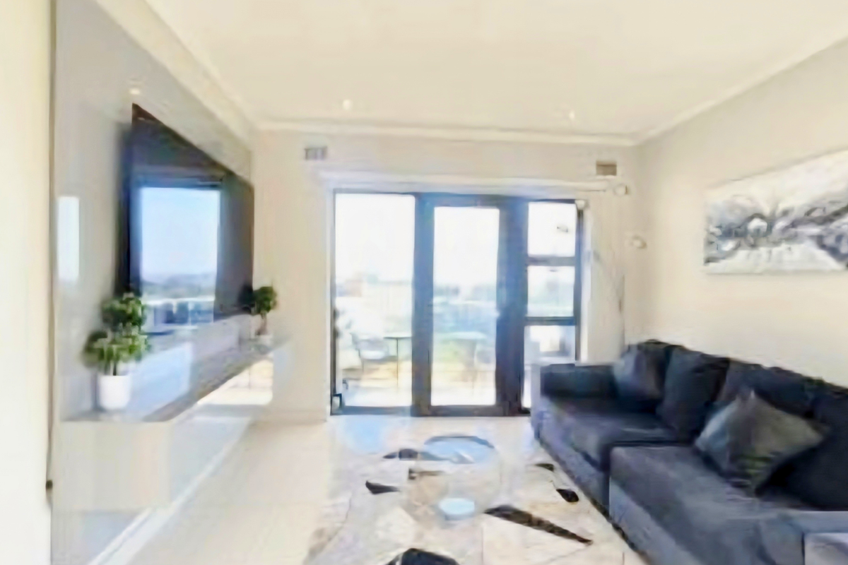 Modern living room featuring a sleek built-in media console, recessed lighting, and large glass sliding doors providing access to an outdoor balcony area.