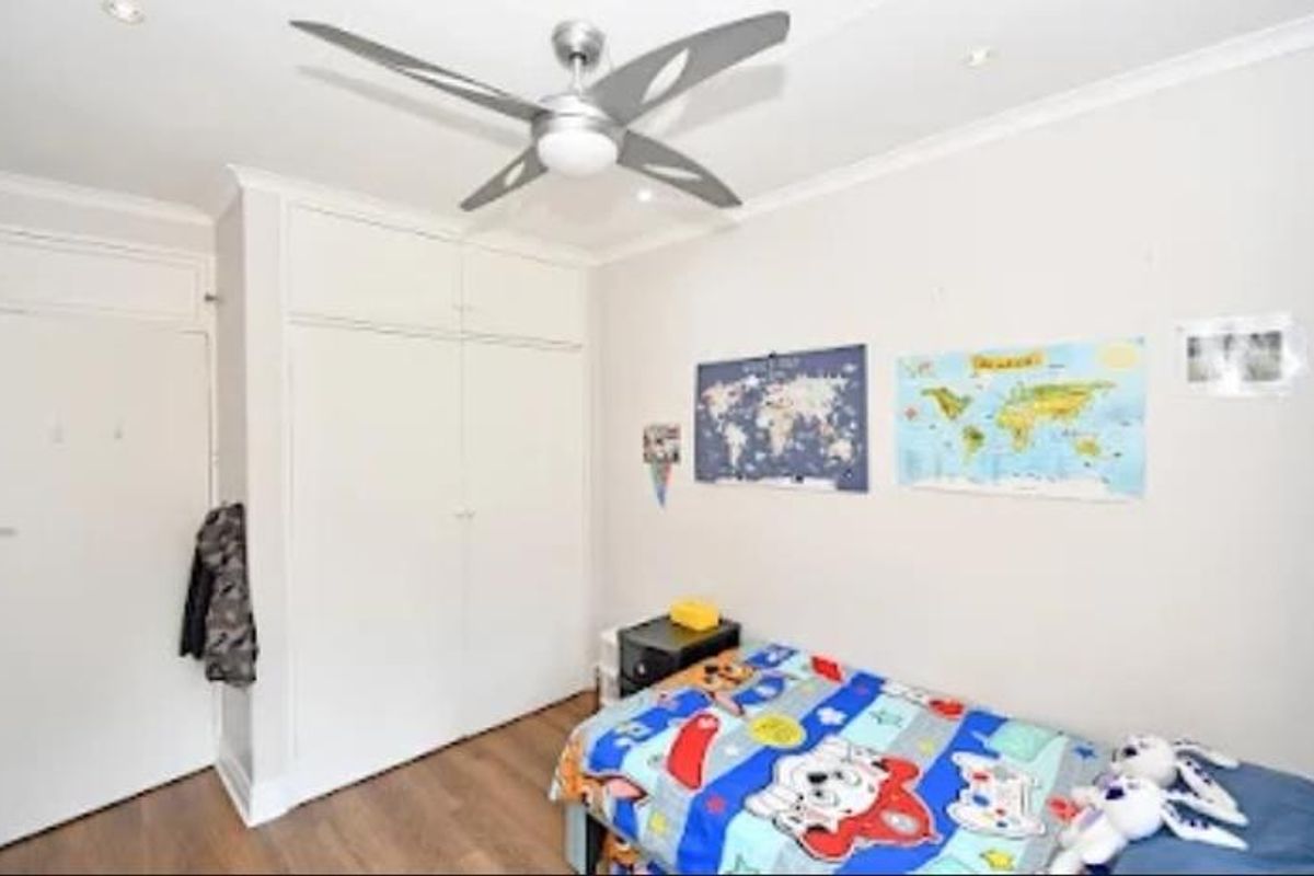 A well-maintained bedroom featuring built-in cupboards, a modern ceiling fan, recessed lighting, and durable laminate flooring.