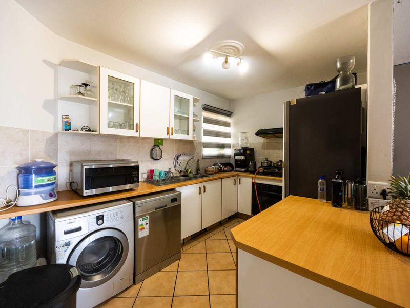 Functional kitchen featuring built-in cabinetry, laminate countertops, tiled backsplash, and integrated cooking appliances with space for laundry and dishwasher units.