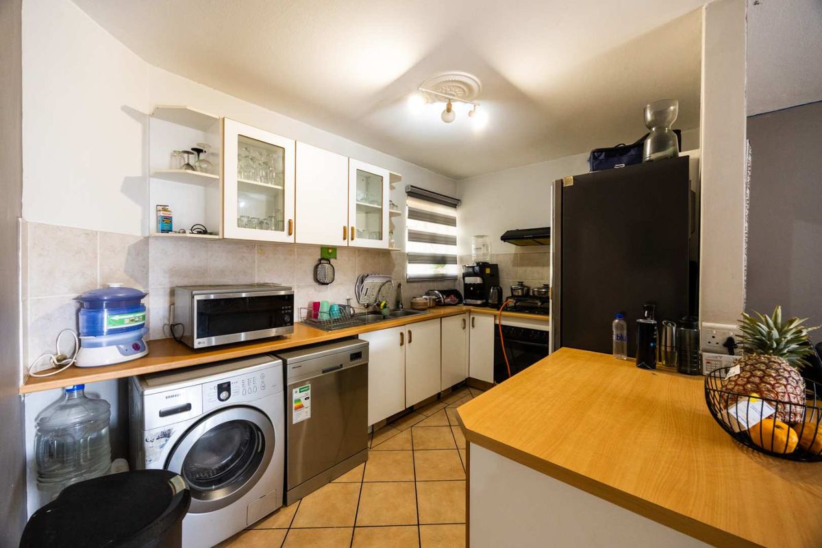 Functional kitchen featuring built-in cabinetry, laminate countertops, tiled backsplash, and integrated cooking appliances with space for laundry and dishwasher units.