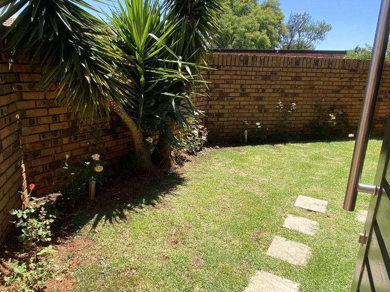 A private rear garden area featuring a well-maintained lawn, stone stepping stones, and a sturdy brick boundary wall.