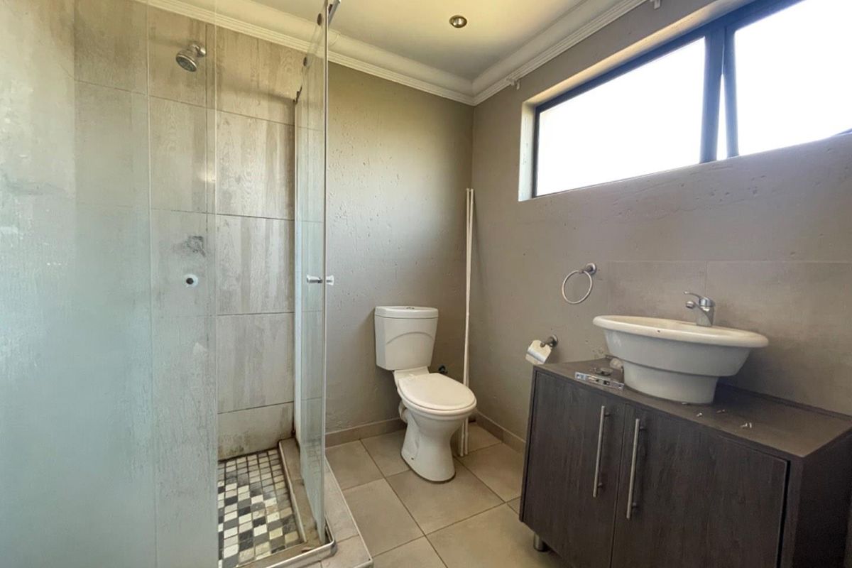 A functional bathroom featuring a glass-enclosed shower, a modern vessel sink on a vanity cabinet, and neutral wall finishes.
