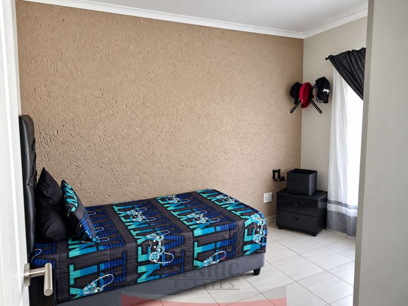 A bedroom featuring tiled flooring and a textured accent wall, providing a neutral base for personalization.