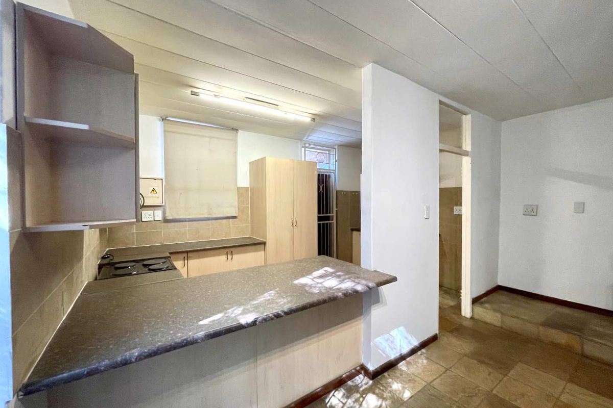 A functional kitchen area featuring built-in cabinetry, a breakfast bar, and tiled flooring, providing a practical layout for daily meal preparation.