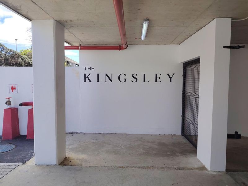 Entrance area of The Kingsley apartment complex featuring concrete flooring, exposed fire safety infrastructure, and a secure gated access point.