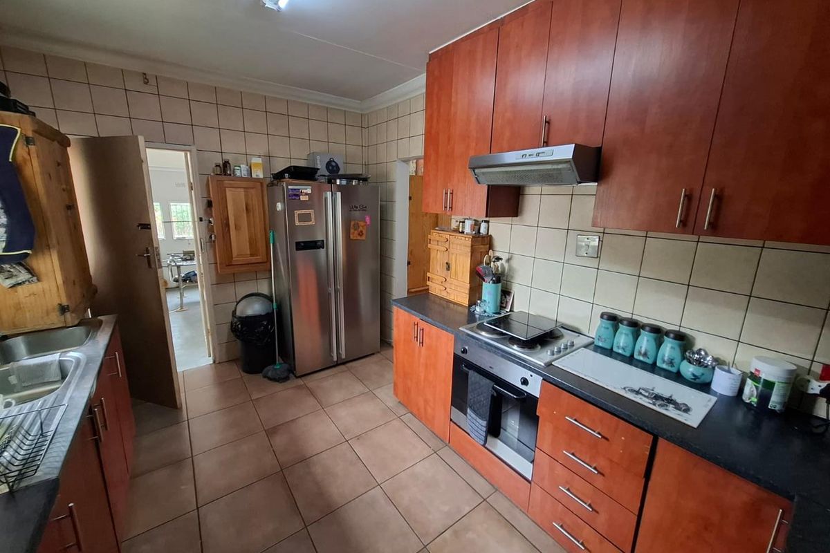 A functional kitchen featuring wood-tone cabinetry, tiled backsplash, and integrated appliances, offering a practical layout with potential for modern cosmetic updates.