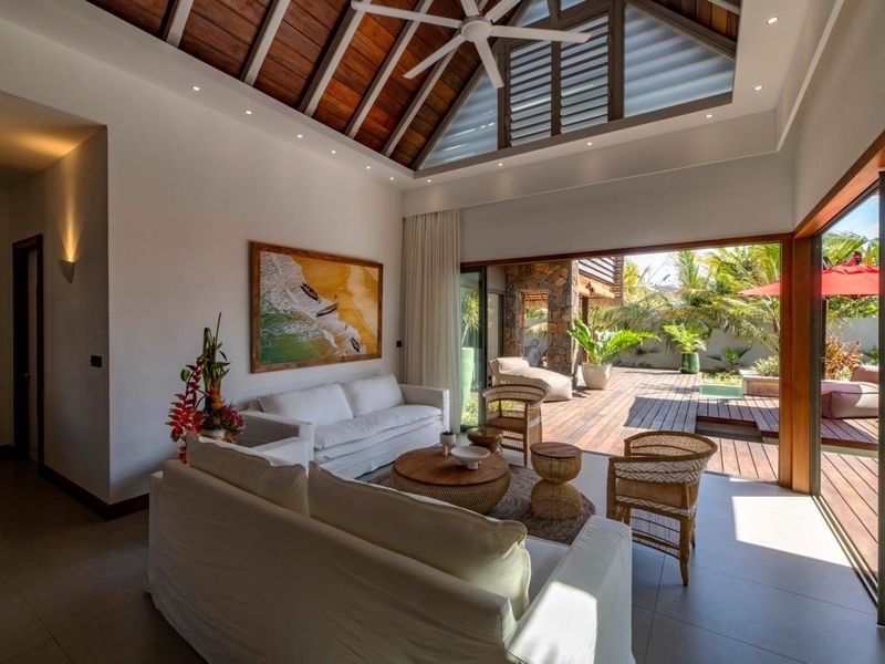 Spacious open-plan living area featuring a high vaulted timber ceiling, recessed lighting, and large sliding glass doors opening onto a wooden deck.