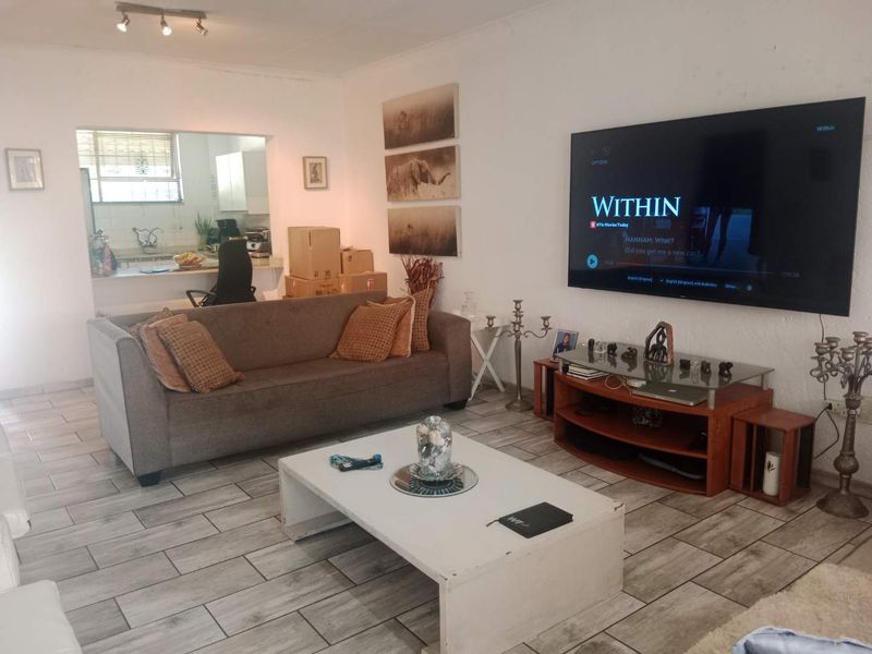 Open plan living area featuring tiled flooring and a convenient pass-through window connecting to the kitchen space.