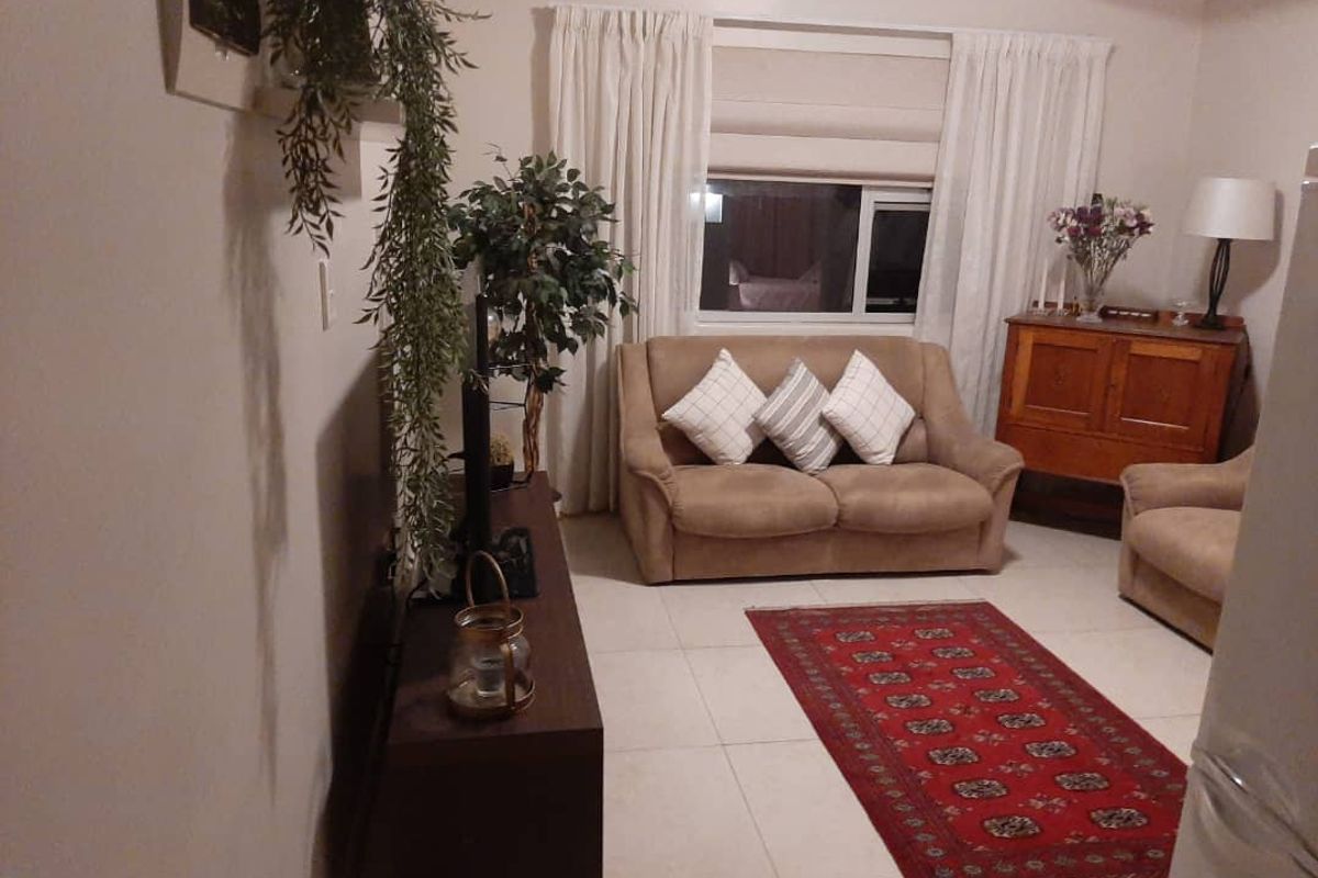 A comfortable living room featuring tiled flooring and a window with curtains, providing a functional and inviting space.