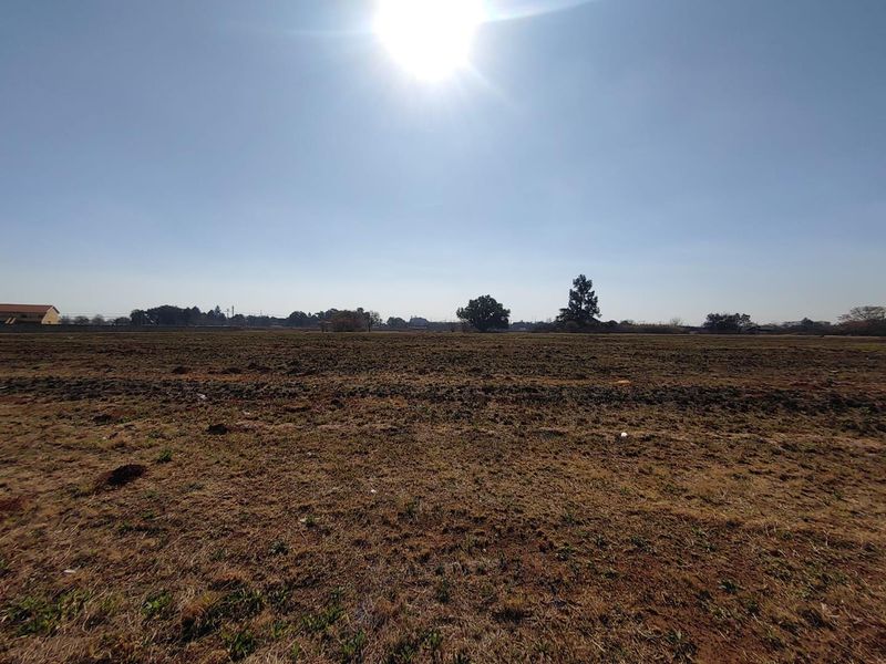 A wide-angle view of a flat, cleared commercial vacant land plot under a clear sky.