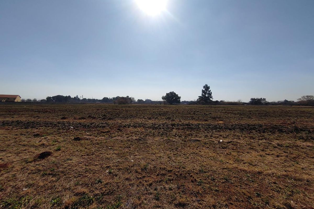A wide-angle view of a flat, cleared commercial vacant land plot under a clear sky.