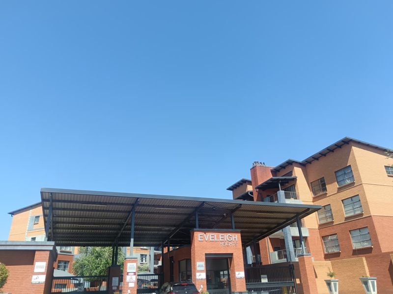 The front entrance of Eveleigh Heights apartment complex, featuring a brick facade, covered security gate, and multi-story residential building structure.